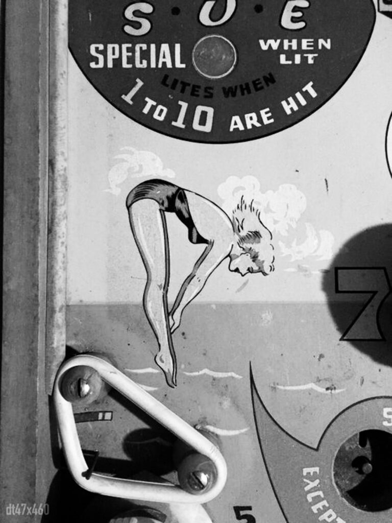 Close Up of pinball game with woman jumping into ocean